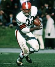 Pro Football Hall of Famer Jim Brown wearing number 32 for the Cleveland Browns rushing the ball